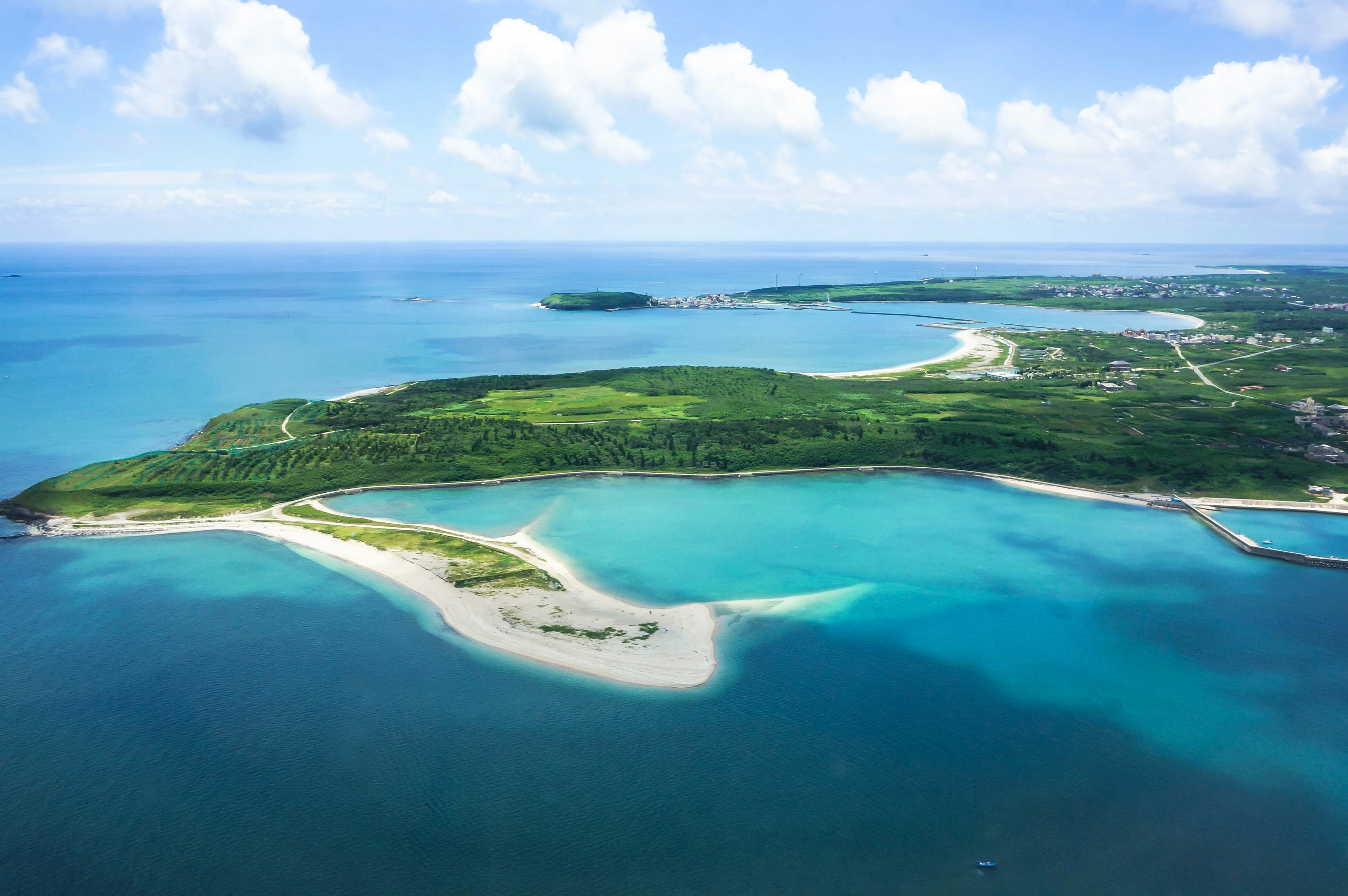 Aerial view of Thailand coastline with turquoise water and lush green hills from skydiving altitude